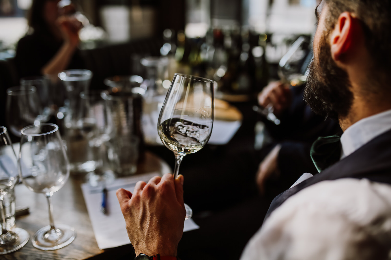 Wine Tasting – a wine taster holding a wine glass, swirling the wine to release its aromas.